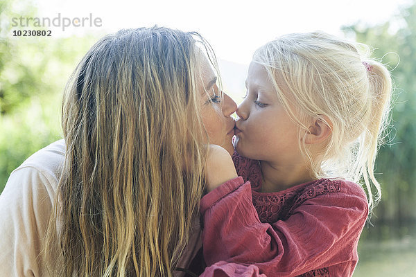 Mutter und Tochter küssen sich im Freien