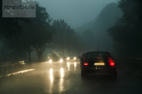 Verkehr auf der Kreisstraße bei Regen in der Dämmerung