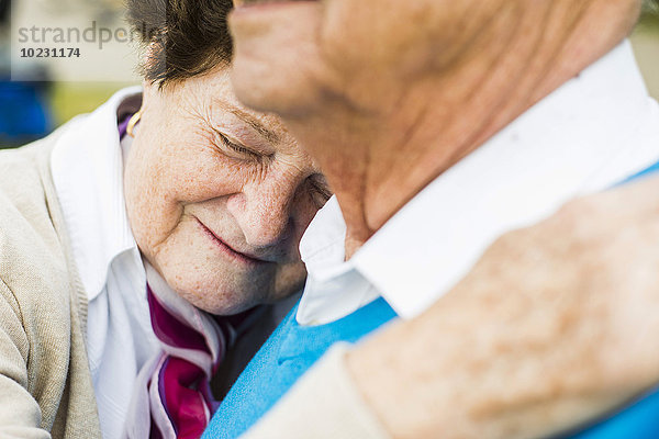 Glückliche Seniorin mit Kopf auf der Schulter ihres Mannes