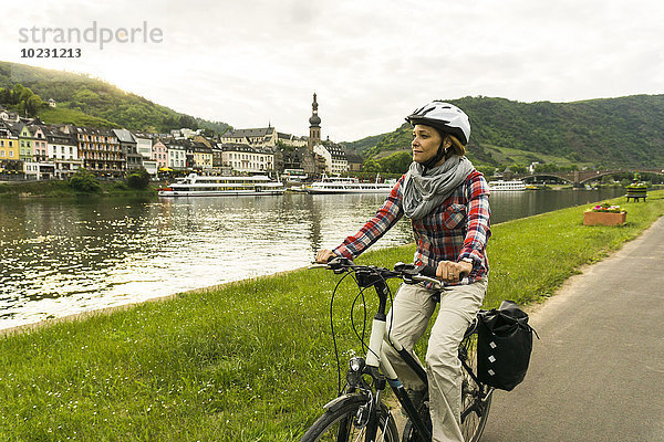 Deutschland  Cochem  Frau auf dem Fahrrad entlang der Mosel