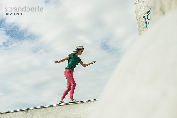 Junge Frau balanciert auf einer Wand in einem Skatepark