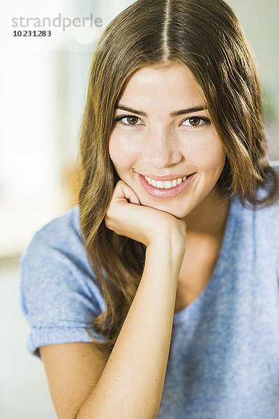 Porträt einer lächelnden brünetten jungen Frau mit Hand am Kinn