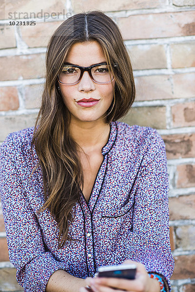 Porträt einer brünetten jungen Frau mit Brille im Freien