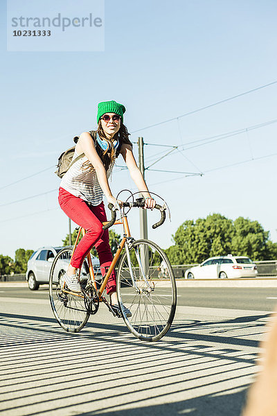 Junge Frau beim Radfahren auf dem Bürgersteig auf der Straße