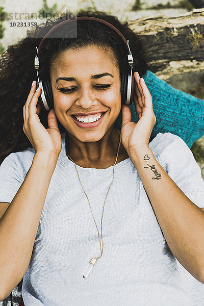 Lächelnde junge Frau mit Kopfhörer im Freien