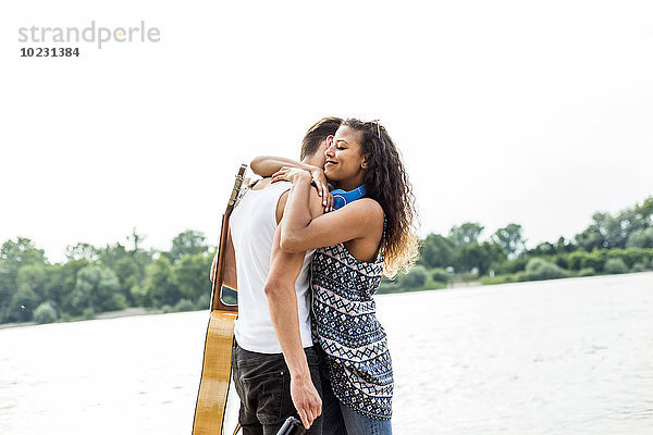 Junges Paar  das sich am Flussufer umarmt