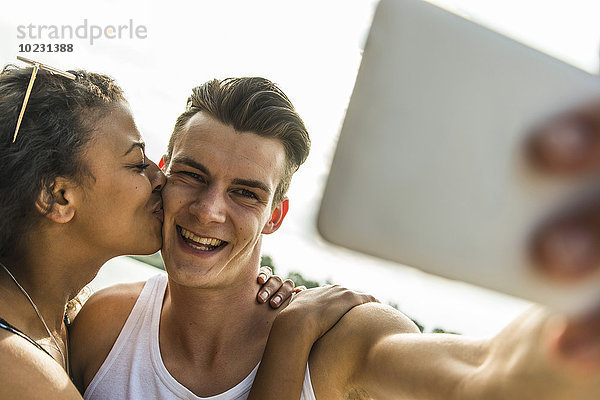 Fröhliches junges Paar mit einem Selfie im Freien