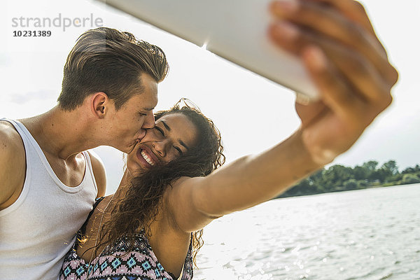 Ein glückliches junges Paar  das einen Selfie am Flussufer nimmt.