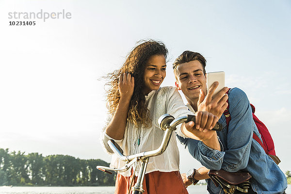 Lächelndes junges Paar mit Fahrrad und Handy