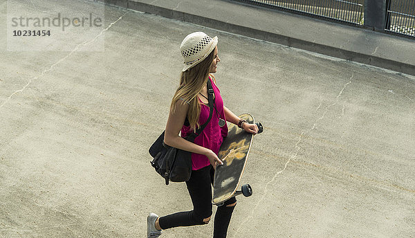 Teenager-Mädchen mit Skateboard unterwegs