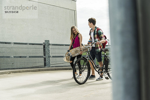 Glückliches junges Paar mit Fahrrad und Skateboard
