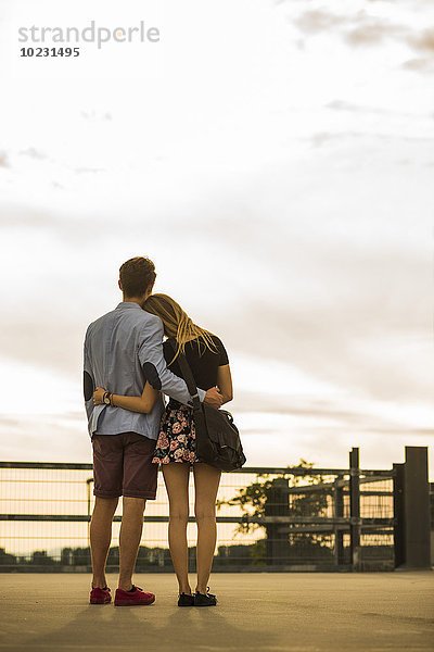 Junges Paar  das sich bei Sonnenuntergang auf Parkebene umarmt