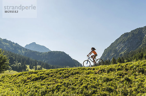 Österreich  Tirol  Tannheimer Tal  junge Frau auf dem Mountainbike in alpiner Landschaft