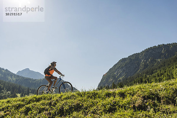 Österreich  Tirol  Tannheimer Tal  junge Frau auf dem Mountainbike in alpiner Landschaft