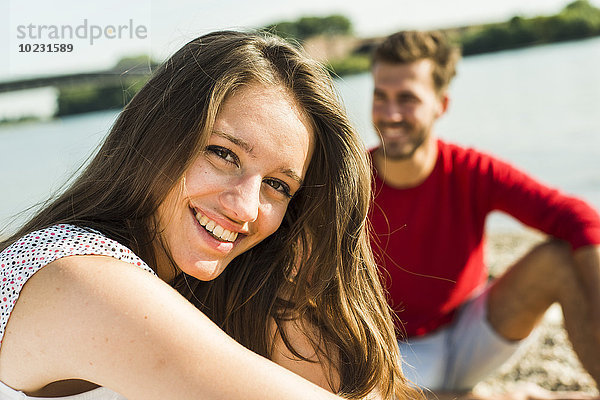 Porträt einer glücklichen jungen Frau mit Mann am Flussufer