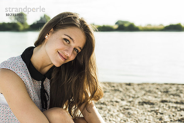 Porträt einer lächelnden jungen Frau am Flussufer