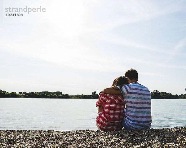Junges Paar am Flussufer sitzend
