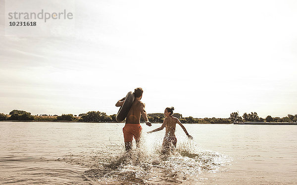 Junges Paar läuft mit Innenrohr im Fluss
