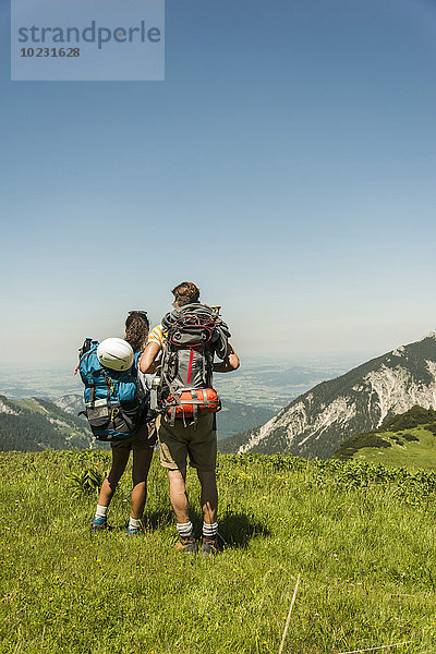 Österreich  Tirol  Tannheimer Tal  junges Paar auf der Alm stehend mit Blick auf die Aussicht