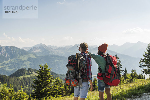 Österreich  Tirol  Tannheimer Tal  junges Paar in alpiner Landschaft mit Blick auf die Landschaft