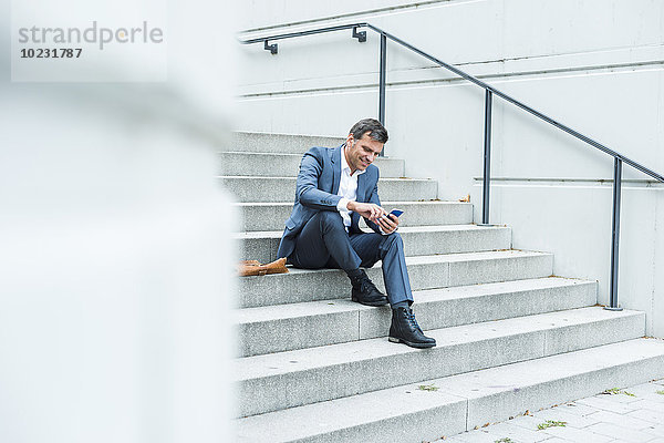 Geschäftsmann auf der Treppe sitzend mit Smartphone