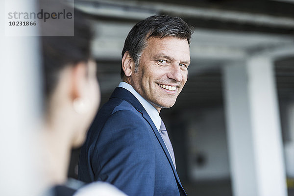 Ein reifer Geschäftsmann lächelt die junge Frau an.