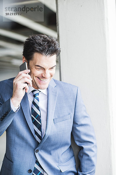 Porträt eines lächelnden Geschäftsmannes beim Telefonieren mit dem Smartphone