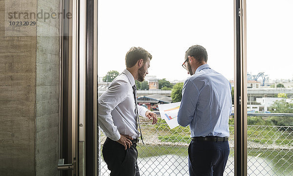 Zwei junge Geschäftsleute schauen sich Dokumente am Fenster an