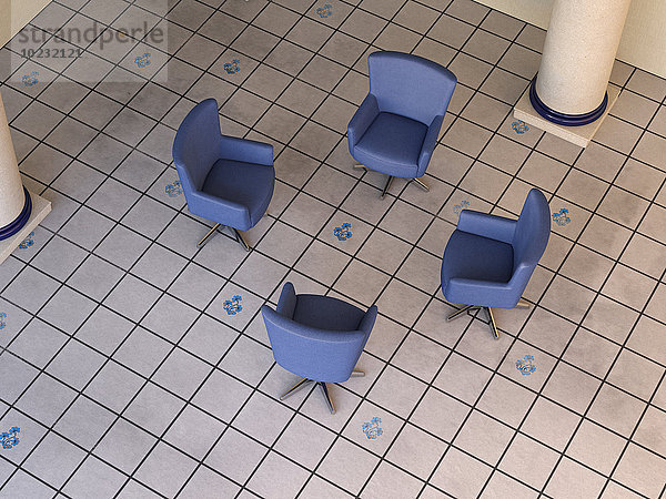 Vier blaue Sessel im Kreis auf Fliesenboden stehend