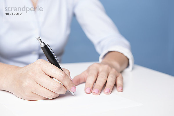 Frau unterzeichnet Dokument auf dem Tisch