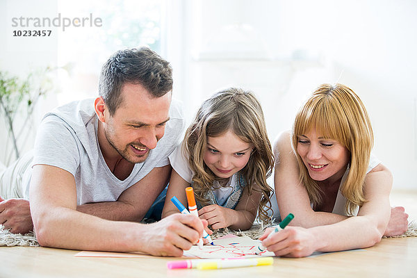 Kleines Mädchen mit Eltern auf dem Boden liegend  Zeichnung mit Filzstiften