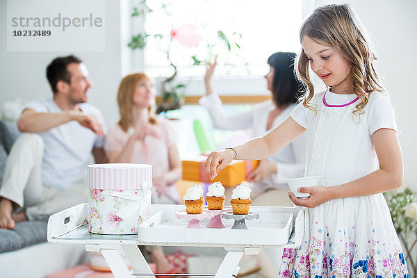 Girl Garnierung Tasse Kuchen  Familie feiert im Hintergrund