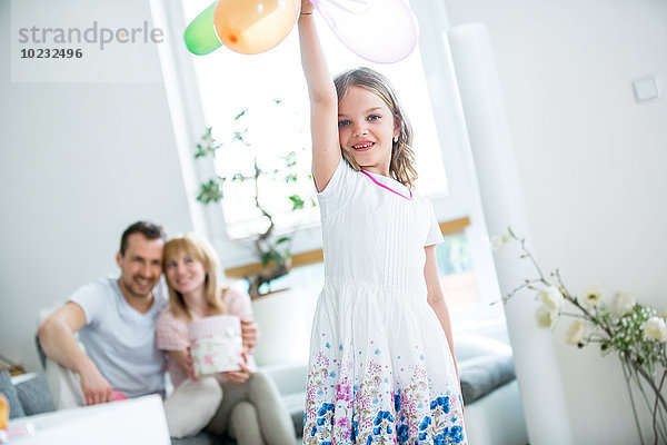 Mädchen spielt mit Luftballons  Eltern schauen zu