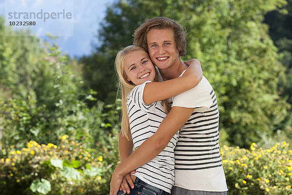Porträt eines umarmenden jungen Paares im Garten