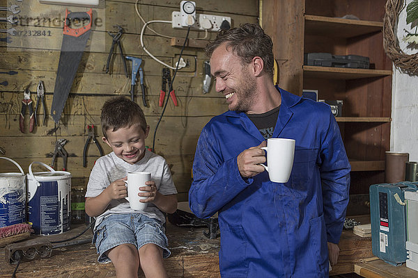 Vater und Sohn arbeiten in der heimischen Garage bei einer Kaffeepause