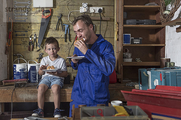 Vater und Sohn arbeiten in der heimischen Garage und machen Mittagspause.