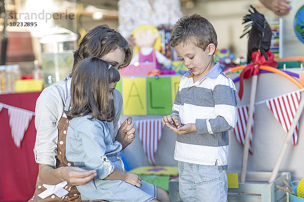 Kinder mit einem Garagenverkauf  der Geld mit der Mutter zählt.