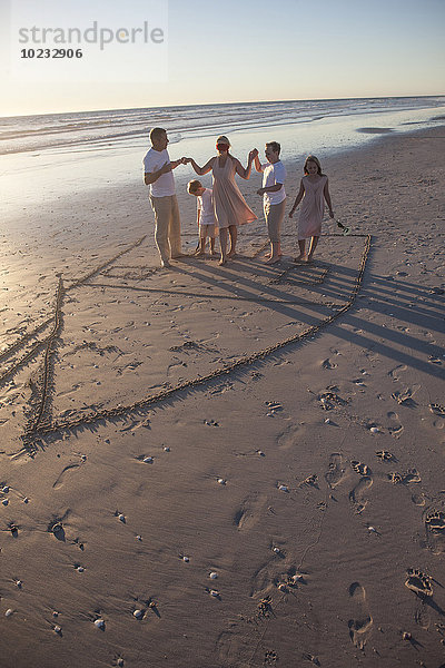 Familie am Strand mit gezeichnetem Haus im Sand