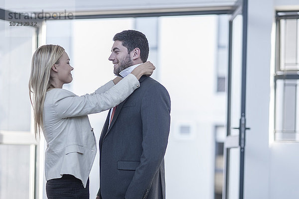 Geschäftsmann  der eine Krawatte anzieht  Frau  die ihm hilft.