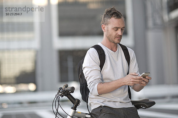 Blone Mann auf dem Fahrrad mit Smartphone