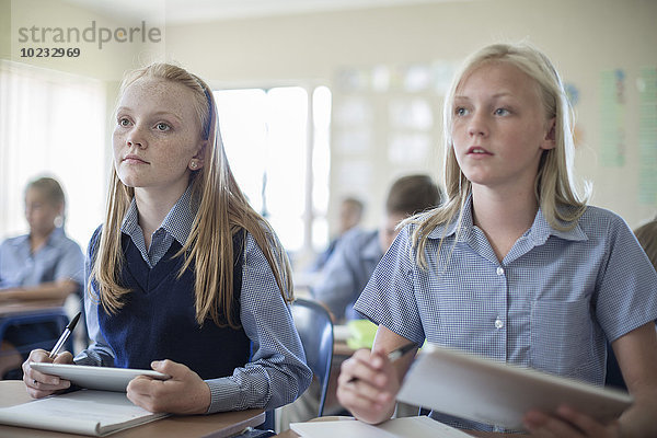 Zwei Schülerinnen im Klassenzimmer mit digitalen Tabletts