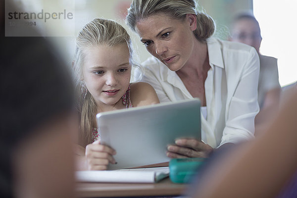 Lehrerin und Schülerin mit digitalem Tablett im Klassenzimmer