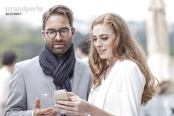 Paar mit Smartphone auf der Terrasse eines Restaurants
