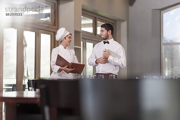 Chefkoch und Kellner im Restaurant diskutieren über das Menü