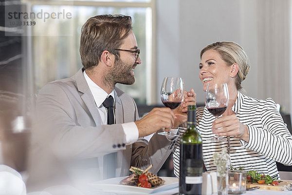 Mittleres erwachsenes Paar im Restaurant Toasting mit Rotwein