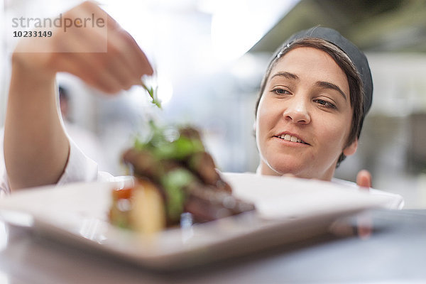 Junger Koch garniert Teller mit Essen