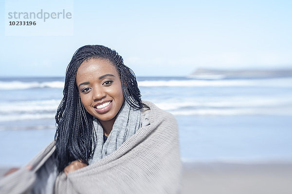 Südafrika  Kapstadt  Porträt einer lächelnden jungen Frau vor dem Meer