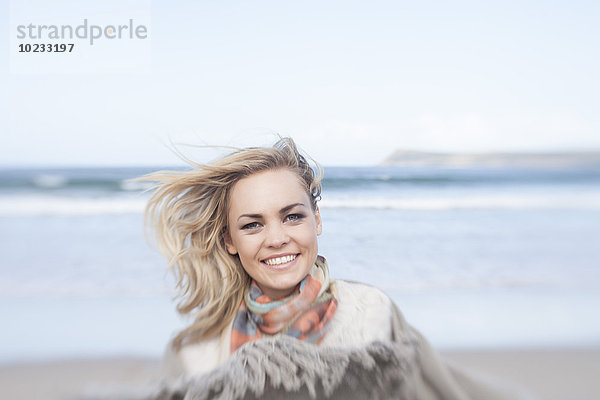 Südafrika  Kapstadt  Porträt einer lächelnden jungen Frau vor dem Meer