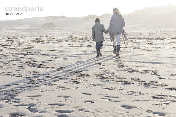 Südafrika  Kapstadt  Mutter und ihr Sohn gehen am Strand spazieren.