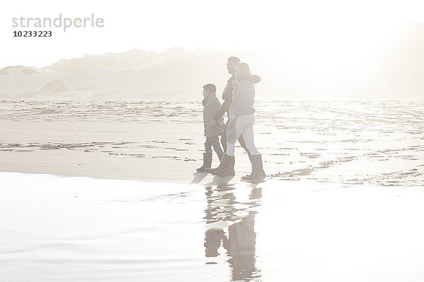 Südafrika  Kapstadt  junges Paar und Sohn beim Spaziergang am Strand im Gegenlicht